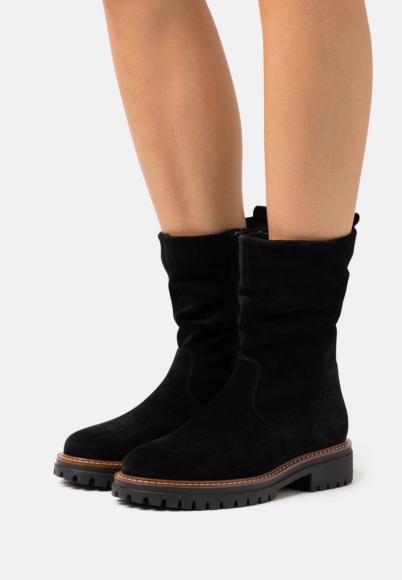 Botines de ante negro con un diseño arrugado, que cuentan con un cierre de cremallera, superficie texturizada y suela de goma resistente con costuras en contraste.