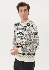 Krem pulover z črnimi geometričnimi vzorci in motivi jelena. Pleten material z okroglo ovratnikom in rebrastimi manšetami.