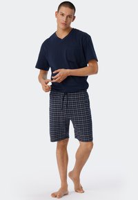 Navy cotton V-neck T-shirt with pocket; paired with knee-length plaid shorts in navy and white, featuring an adjustable drawstring waist.