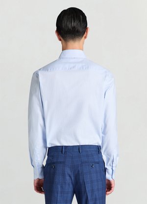 Chemise à manches longues bleu clair avec un col classique, présentant une texture subtile et des poignets boutonnés, associée à un pantalon à carreaux bleu.