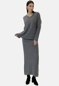Set di maglione a coste grigio e gonna lunga abbinata. Il maglione presenta un collo a V e maniche lunghe; la gonna è ankle-length con una silhouette aderente.