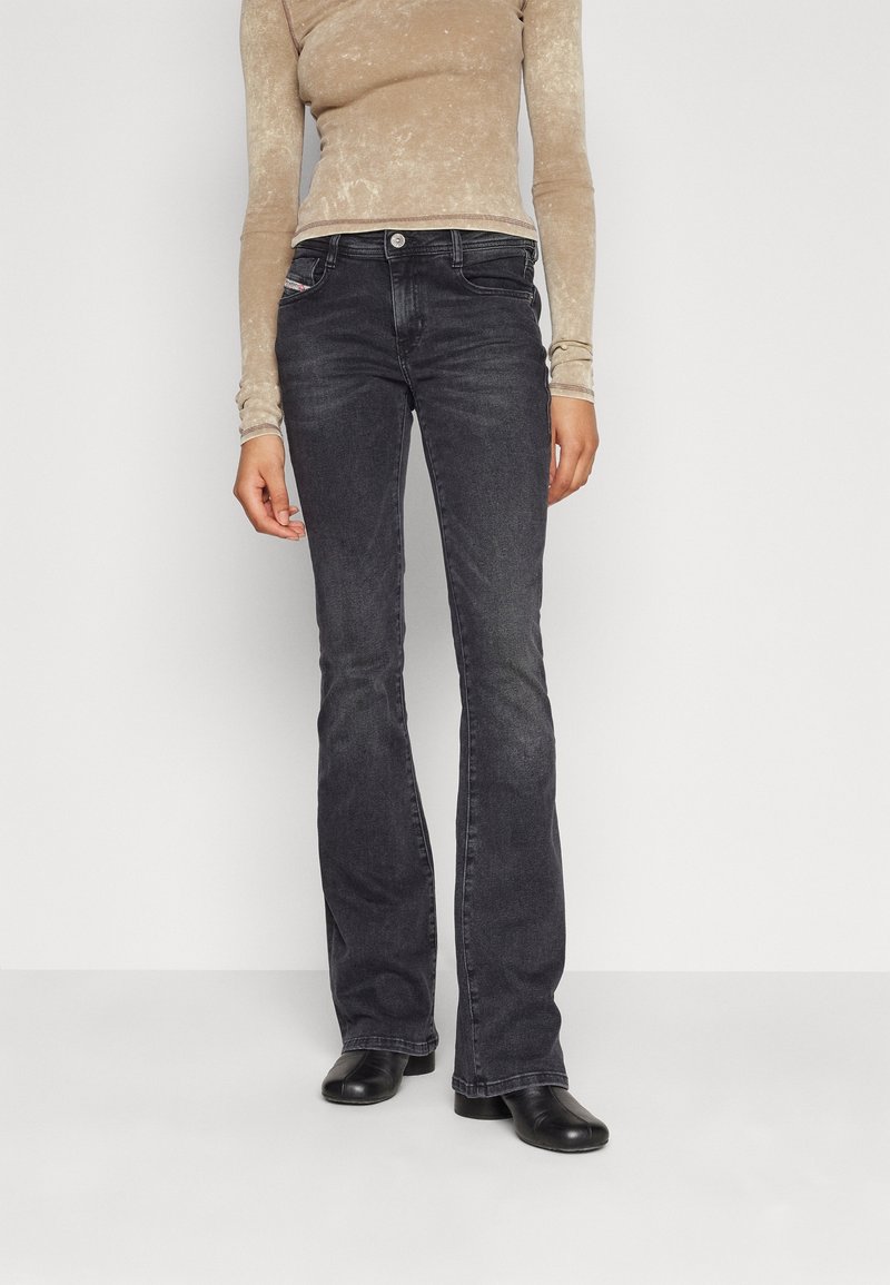 Ciemnoszare dżinsy w fasonie dzwonów, wykonane z denimu, z klasycznym pięciopunktowym wzornictwem i metalowym zapięciem. Gładka faktura i minimalne detale.