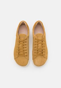 Cordfløyels sneakers i sennepsgul med rund tå, hvit gummisåle og tonede snørebånd. Har preget merkevarelogo på innersålen.