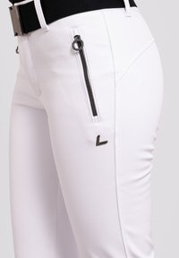 Weiße Hose aus Stretchstoff, mit einer seitlichen Reißverschlusstasche mit einem schwarzen Reißverschluss und einem kleinen silbernen Logoakzent am Oberschenkel.
