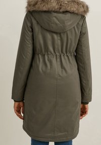 Płaszcz parka w kolorze khaki z kapturem wykończonym sztucznym futrem, elastycznym pasem i ściągaczami na mankietach. Gładka tkanina z przeszyciami zdobiącymi plecy.