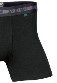 Musta bokseritrikoot, jotka on valmistettu joustavasta kankaasta. Niissä on tumma vyötärönauha, jossa lukee "JBS UNDERWEAR", sekä pieni vihreä etiketti.