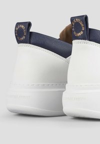Sneakers bianchi in pelle con una tomaia in tessuto navy testurizzato, dotati di un interno marrone a contrasto, e marchiatura in rilievo sul tallone e sul loop di estrazione.