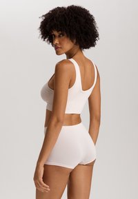 Ljust rosa sömlös bh och matchande boyshorts, tillverkade av mjukt tyg, med en rundad neckline och breda axelremmar för stöd.