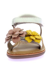 Sandalia de cuero blanco con aplique floral en beige y amarillo. Diseño de punta abierta, correa ajustable y plantilla acolchada con suela marrón.