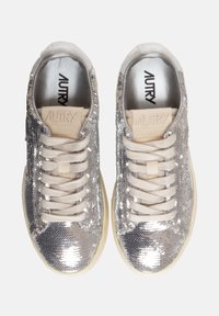 Sneakers argentati con paillettes, dal profilo basso, dotati di lacci beige, una morbida fodera grigia e una suola bianca sottile.