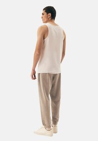 White tank top and light gray sweatpants, displayed from the back. The tank is simple, sleeveless, and fitted; pants have elastic cuffs.