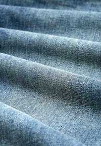 Tela de mezclilla en azul claro, con una textura suave, un ligero brillo y un patrón de tejido diagonal distintivo.