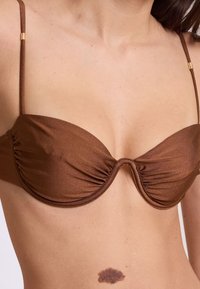 Bikini top metallico marrone con coppe morbide, dettagli arricciati, spalline sottili regolabili e sottili accenti in metallo dorato.
