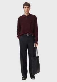 Burgundy long-sleeve polo sweater with a collar, black trousers, and a textured black tote bag. Simple design and tailored fit.