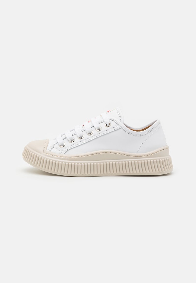 Sneaker bianca in pelle con punta arrotondata, cuciture tono su tono e una suola in gomma beige spessa con scanalature orizzontali e dettagli.