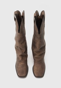 Braune Leder-Cowboy-Stiefel mit einem lässigen Design, spitz zulaufenden Zehen und Aussparungen am oberen Rand. Glatte Textur mit matter Oberfläche.