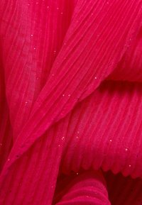 Tejido texturizado de color rosa brillante con un diseño arrugado. Presenta finos destellos, añadiendo un sutil brillo a la superficie.