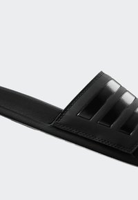 Black slide sandal with a glossy upper featuring three horizontal stripes, a matte adjustable strap, and a textured footbed.