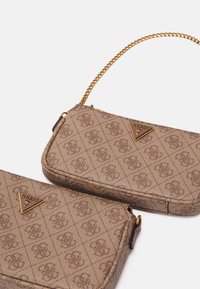 Torby z materiału w brązowy wzór z metalowymi elementami w kolorze złotym; posiadają pasek na łańcuszku i trójkątny detal z logo. Gładka tekstura z pikowanym wzorem.