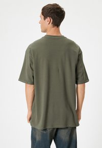 Olivegrøn oversized T-shirt lavet af blødt bomuld, med korte ærmer og rund halsudskæring. Synlig syning på forneden.