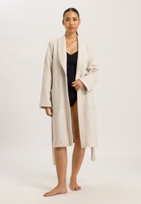 Accappatoio avvolgente beige realizzato in morbido pile, con colletto a scialle, maniche lunghe e due tasche frontali. Tessuto liscio, design di lunghezza media.