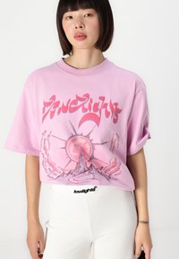 Pink oversized t-shirt featuring a graphic design with a sun and abstract elements. Soft cotton material, relaxed fit, with light, casual style.
