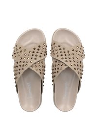 Beige slide sandals with crisscross design, adorned with metallic studs. Smooth texture, open back, and slightly raised soles.