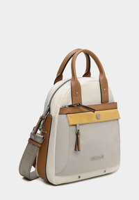 Bolso bicolor con cuerpo crema y beige, asas de cuero marrón y un acento frontal amarillo. Presenta herrajes en plata y una correa ajustable.