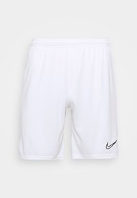 Pantalones cortos deportivos blancos con cintura elástica y logo negro de Nike en la parte inferior de la pierna derecha, exhibidos sobre un fondo plano.