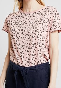 Camiseta de manga corta rosa con un diseño de estampado de leopardo negro, hecha de tela suave, con escote redondo y corte relajado.