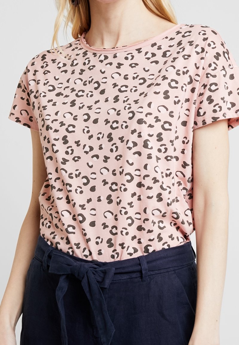 Camiseta de manga corta rosa con un diseño de estampado de leopardo negro, hecha de tela suave, con escote redondo y corte relajado.