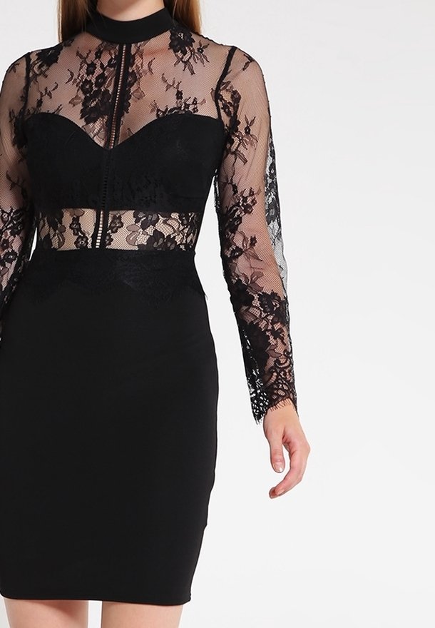 Svart klänning med en spetskorsett, långa ärmar, hög halsringning och en figursydd kjol. Spetsdetaljer framhäver midjan och ärmarna.