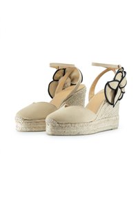 Scarpe in tela beige con zeppa in juta intrecciata. Presentano un accento floreale nero sul tallone e una cinghia alla caviglia per una vestibilità sicura.