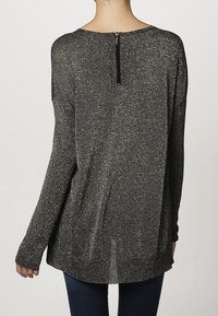 Pull noir avec fil métallique, col rond, manches longues et fermeture éclair à l'arrière. Forme évasée avec une texture douce.