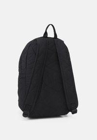 Zaino nero trapuntato con spallacci regolabili, caratterizzato da un motivo geometrico sul tessuto e una maniglia superiore per un facile trasporto.