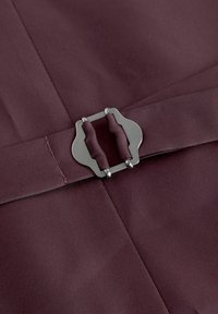Tissu bordeaux avec une texture lisse, présentant une boucle en métal argenté à la forme unique, mettant en valeur un design ajusté.