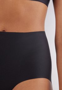 Högmidjade svarta bikiniunderdelar med en mjuk textur och bred midjeband, designade för komfort och en säker passform.