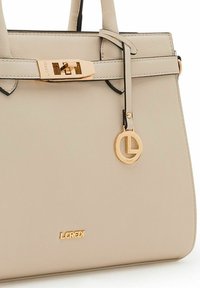 Beige leren handtas met gestructureerd ontwerp, gouden hardware, zwarte accenten en een hanger met een cirkelvormig logo. "L. Credi" merknaam weergegeven.