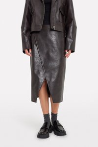 Brown leather midi skirt with a side slit, textured finish, and sleek design, paired with black platform shoes and gray socks.