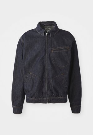 Veste en denim bleu foncé avec une fermeture éclair devant, col pointu, ourlet élastique et deux poches avant ; présente des coutures orange contrastantes.