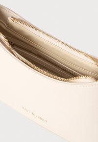 Kremasta Valentino torba s teksturiranom površinom, zip pregradama i zlatnim hardverom, s utisnutim logotipom na vanjskoj strani.