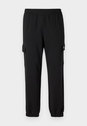 Schwarze Sweatpants mit einem elastischen Bund, schmal zulaufenden Bündchen und seitlichen Cargo-Taschen. Hergestellt aus weichem Material mit einer glatten Textur.