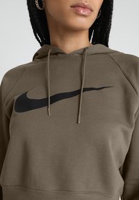 Olivgrön hoodie i mjukt tyg, med en stor svart Nike-logotyp på bröstet, med dragsko i huvan och ribbade muddar.