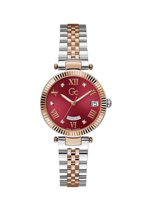 Ceas rotund de damă cu curea metalică bicoloră, cadran roșu, cifre romane aurii, marcatori cu diamante, afișaj zi și dată la orele 3 și 6.