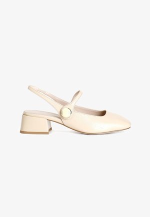 Zapato beige tipo slingback con punta cuadrada, tacón bajo y tira al tobillo con un acento de botón redondo. Textura suave, similar al cuero.