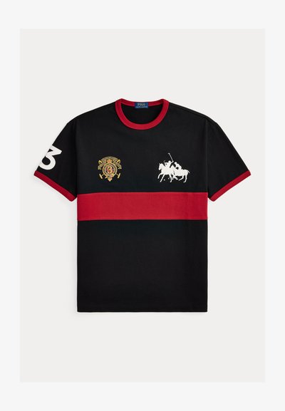 Μαύρο πόλο μπλουζάκι με κοντό μανίκι, κόκκινη οριζόντια ρίγα, κόκκινο γιακά και άκρες στα μανίκια, λευκά λογότυπα παίκτη πόλο και ο αριθμός 3 στο μανίκι.