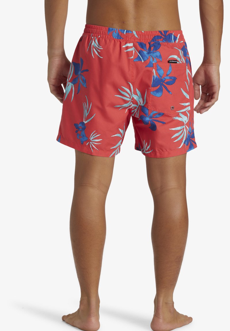 Bañador rojo con patrón floral tropical en azul y blanco, cinturilla elástica y bolsillo trasero con cierre de botón, hecho de material ligero.