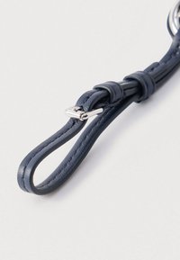 Tamnoplavi kožni remen glatke teksture s petljastim dizajnom i sjajnom srebrnom metalnom kopčom za sigurno pričvršćivanje.