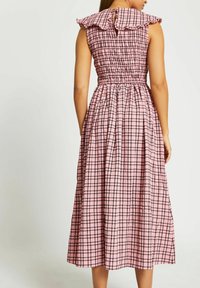 Rosa rutigt klänning med smockad byst och volangkrage. Har en midislängd kjol och nyckelhålsöppning bak.