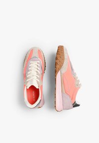 Zapatillas en rosa y gris con una parte superior de ante y malla, suela de goma texturizada, puntera redonda y acentos en contraste. Los cordones son de color crema.